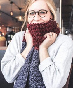 Suzette stitch long crochet scarf in burgundy and blue worn in a coffee shop