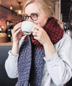 Suzette stitch long crochet scarf in burgundy and blue worn in a coffee shop