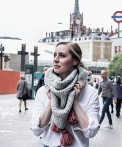 Oversized crochet triangle scarf in grey with pink tassels, worn at Kings Cross London